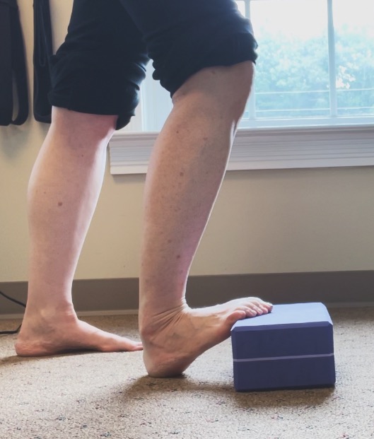 female doing a calf stretch on yoga block to prevent toe cramps