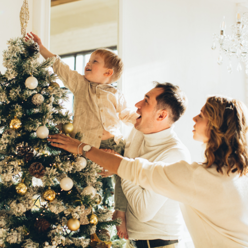 a family of three decorating a christmas tree. 