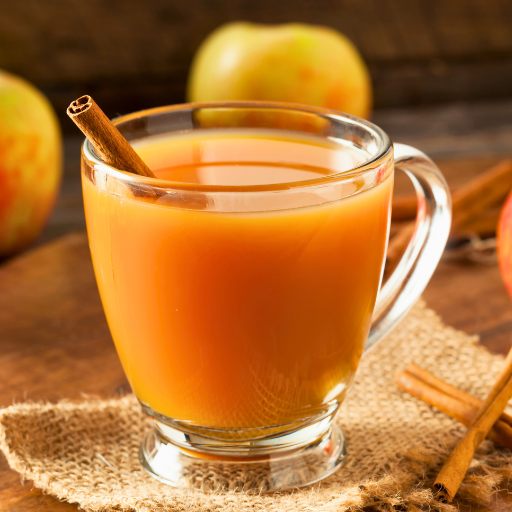 apple cider in a clear mug with a cinnamon stick