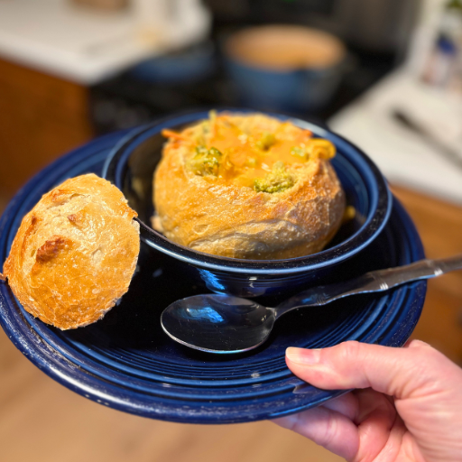 holding a bowl of broccoli cheddar soup in a bread bowl