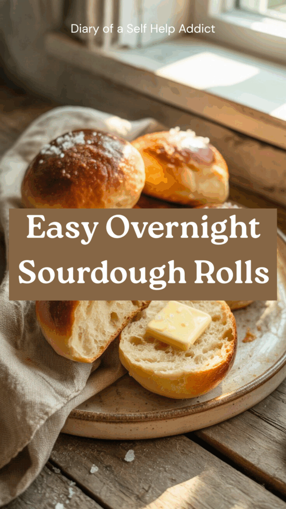 A plate of beautifully browned sourdough rolls, one sliced open with melted butter and flaky sea salt, cozy napkin beside it, rustic vibes.