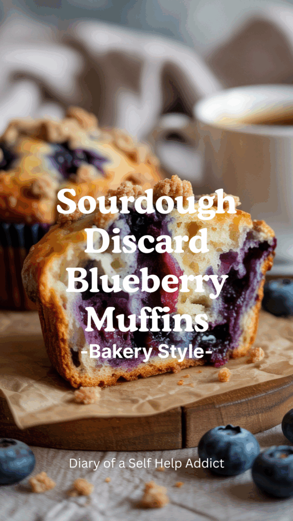 Close-up of a sliced sourdough blueberry muffin showing a moist crumb and juicy blueberries inside. Crumb topping sprinkled on top, a cup of coffee beside it, soft neutral background with cozy textures.