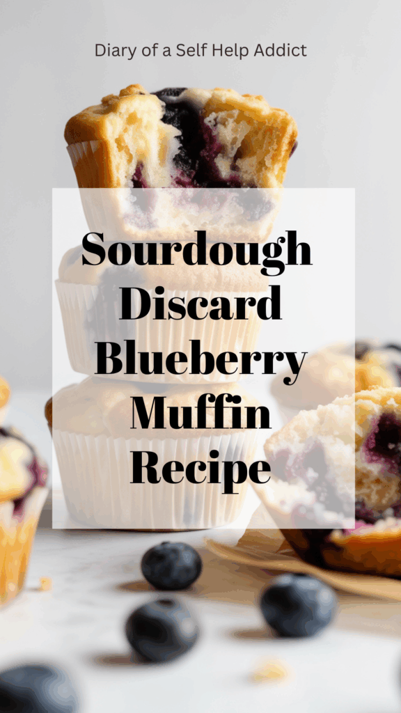 Stack of three blueberry muffins with visible crumb topping, one broken open to show texture. Blueberries rolling around, white background, minimalist food photography style, soft natural lighting.