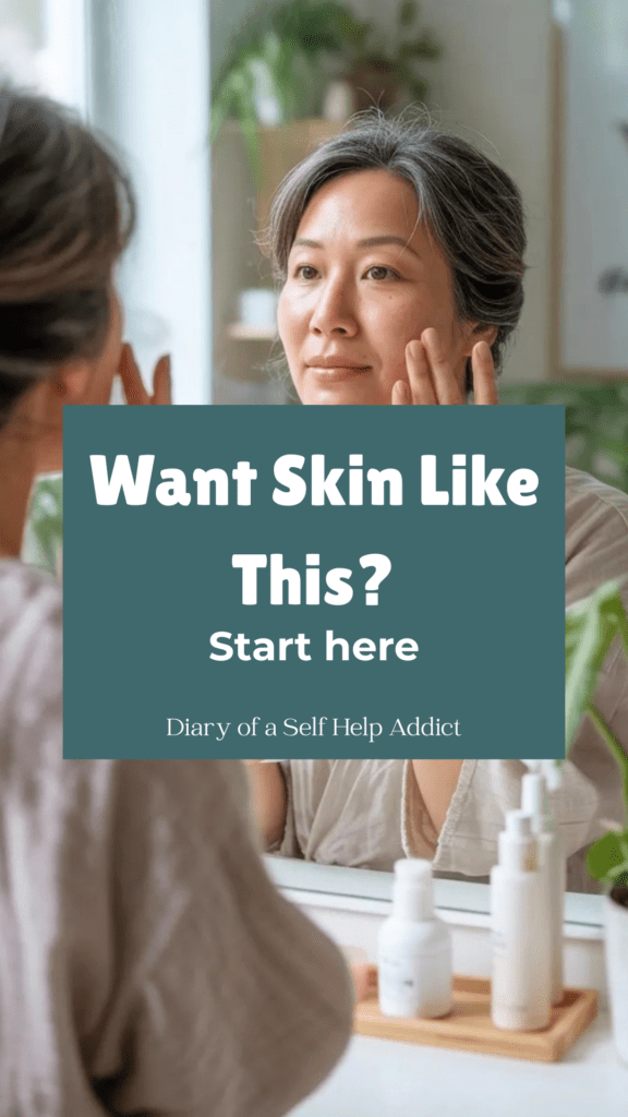 Soft, glowing morning light in a calm, minimal home. A woman in her 40s or 50s with natural, radiant skin is applying skincare in front of a mirror. Neutral tones, clean space, plants, peaceful mood. Skin looks hydrated and healthy, not overly made up.