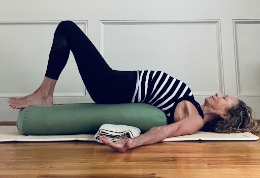 Beth Passehl doing inverted savasana yoga pose on a bolster.