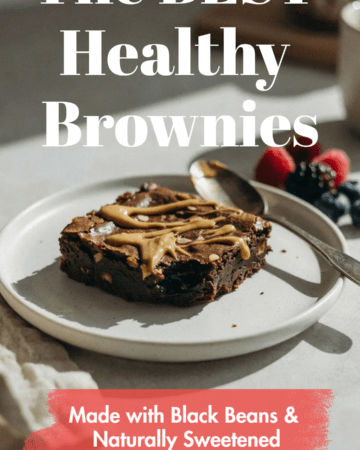 A brownie served warm with a spoonful of almond butter drizzled over the top and fresh berries on the side. Neutral kitchen background with soft morning sunlight.