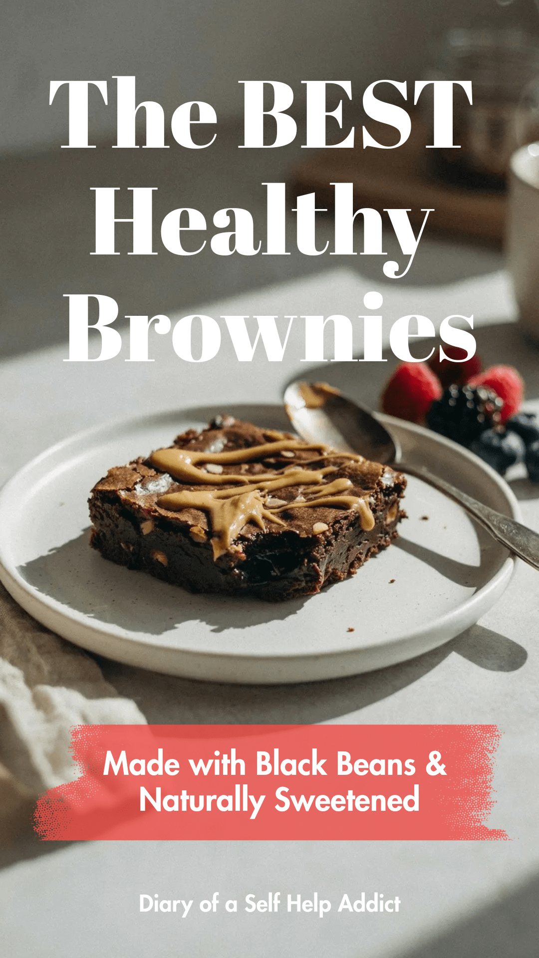 A brownie served warm with a spoonful of almond butter drizzled over the top and fresh berries on the side. Neutral kitchen background with soft morning sunlight.