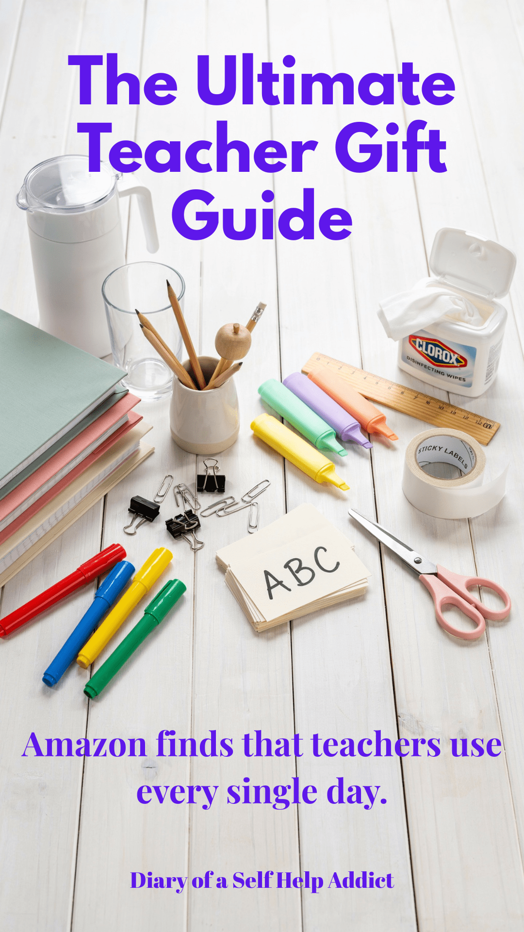An aesthetically pleasing collection of classroom essentials neatly arranged on a white wood background including disinfecting wipes, water pitcher, binders, highlighters, flash cards, labels, markers, scissors, and office supplies. Bright, clean, Pinterest-worthy style.