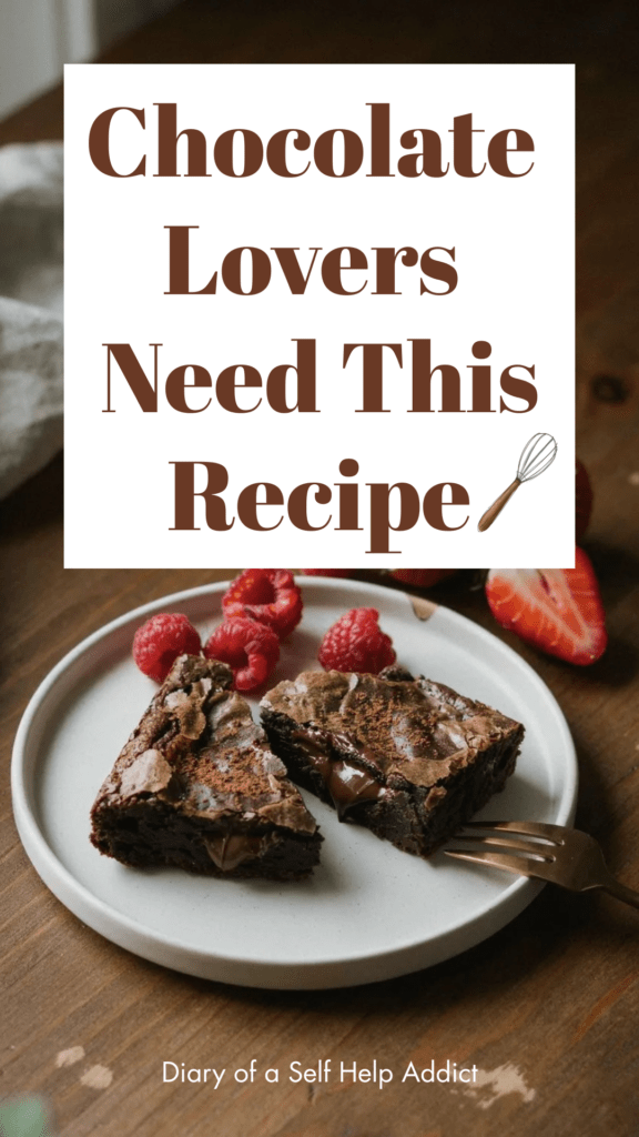 A brownie broken in half to reveal the gooey chocolate center with melted chocolate chips. Fresh raspberries and strawberries surround the plate on a rustic wooden table.