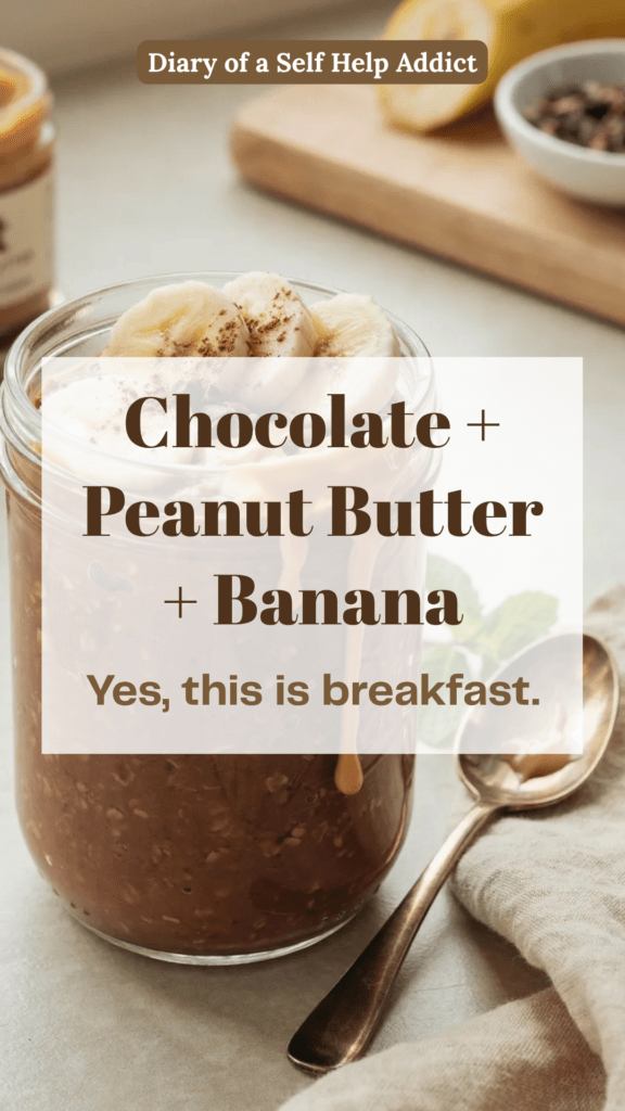 A decadent-looking jar of chocolate overnight oats topped with sliced banana and a creamy drizzle of PBfit peanut butter. A light dusting of cocoa powder and a few cacao nibs on top. Cozy kitchen setting with a spoon beside the jar. Make it look rich and dessert-like while still clearly being a healthy breakfast.