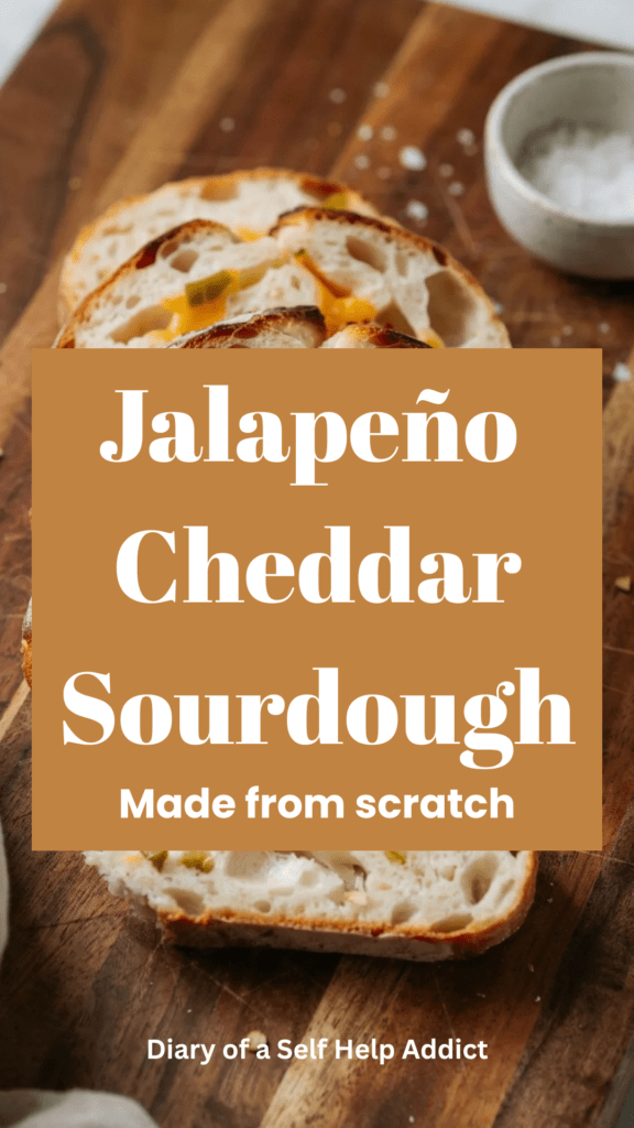 A close-up of several slices of jalapeño cheddar sourdough showing the soft, airy crumb filled with melted pockets of creamy cheddar and little pieces of jalapeño. The crust is crisp and golden, with a rustic wooden background and warm natural light.
