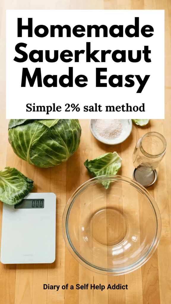 An overhead photograph on a warm, neutral kitchen counter featuring one fresh green cabbage, a small dish of Redmond Real Salt, a digital kitchen scale, a large glass mixing bowl, and an empty Mason jar. A few loose cabbage leaves are arranged naturally around the ingredients. The image should feel bright, approachable, homemade, and uncluttered—not overly styled.