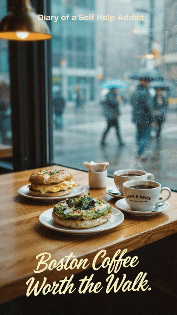 A close-up of coffee beside your avocado bagel, with Natalie’s coffee and egg bagel sandwich across the table. A rainy café window in the background adds to the relaxed morning atmosphere. Text: “Boston Coffee Worth the Walk.”